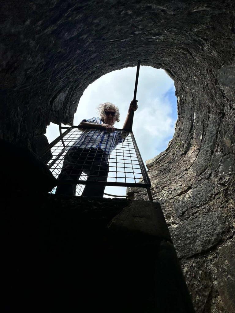 Photo of Carlos Palacios looking down the entrance of a stone stairwell leaning on a metal rail.