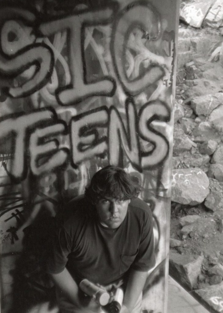 Carlos Palacios posing in front of a graffitied Sicteens sign in Colorado Springs circa 1995.