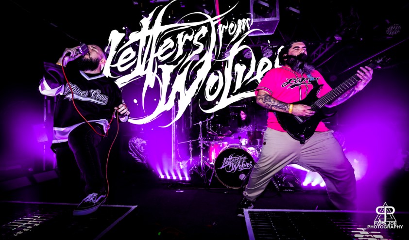 Photo of El Paso metal band Letters From Wolves during a live performance. The band's singer is at the front left of the stage, guitarist is at the front right of the stage and the drummer is in the center in the back.