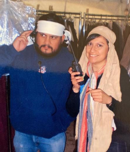 Photo of Omar Leopolo "Polo" Torres and Olivia "Tina" Torres, a brother and sister from El Paso, Texas, wearing head scarves from a film costume truck, and using a walkie talkie and headset.