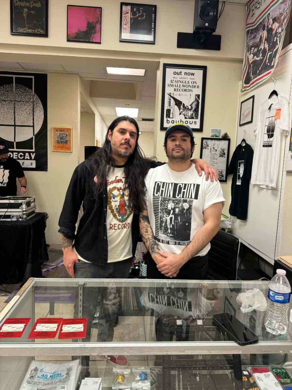 Photo of brothers and co-owners of downtown El Paso, TX record store, Sound Decay Records, standing in front of the counter at their store. Their names are Abel Salazar, left, and Danny Alcantar.